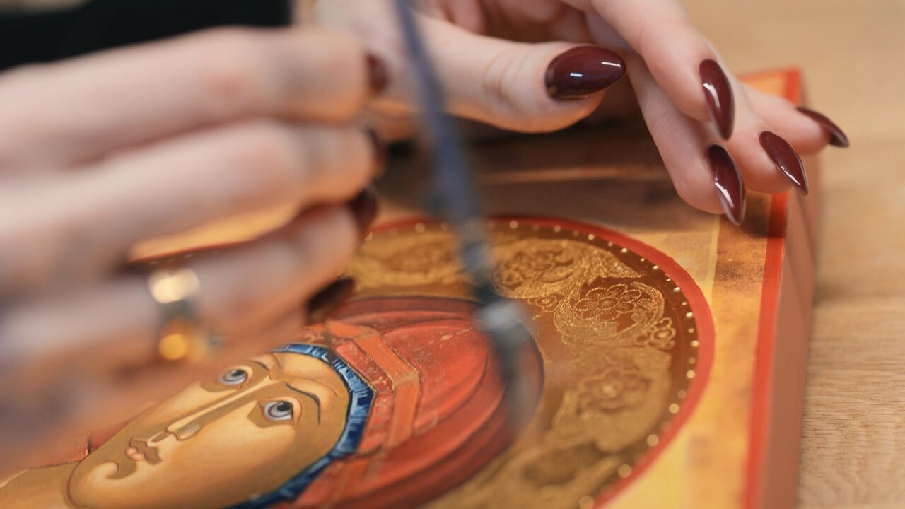 Macro: a brush laying gold along the shoulder-piece ornament