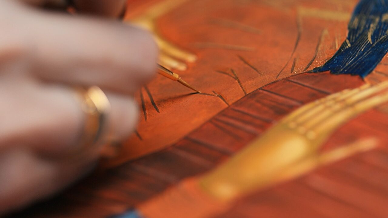 A brush laying gold over dried tempera